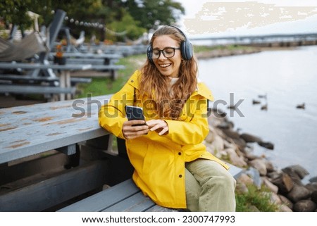 Young woman listens to music, audiobook or podcast outdoors. Communication in social networks. Lifestyle.
