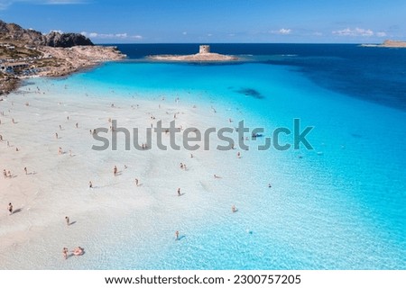 Aerial view of famous La Pelosa beach at sunny summer day. Stintino, Sardinia island, Italy. Top view of sandy beach, swimming people, clear blue sea, old tower and sky with clouds. Tropical seascape Royalty-Free Stock Photo #2300757205
