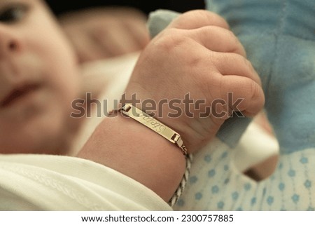 A baby with a golden bracelet after the christening ceremony Royalty-Free Stock Photo #2300757885