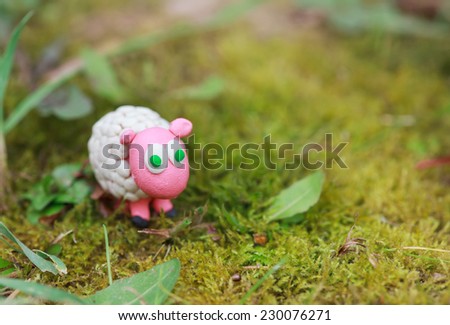 Plasticine world - little homemade white sheep with green eyes, selective focus and place for text