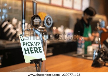 "Pick up here", the self service banner sign at the food reastaurant or beverage counter bar. Sign and symbol object photo, selective focus.