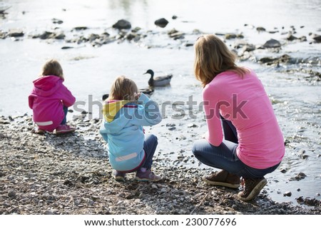 Mother with twin girls playing at river