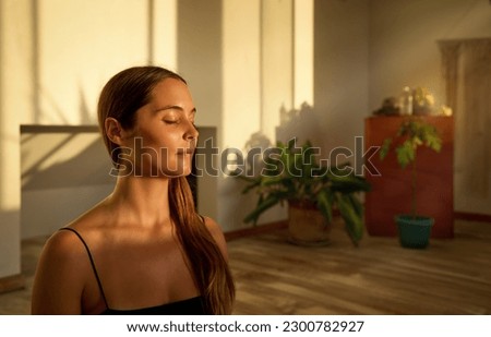 portrait young caucasian woman sitting with closed eyes meditating indoors Royalty-Free Stock Photo #2300782927