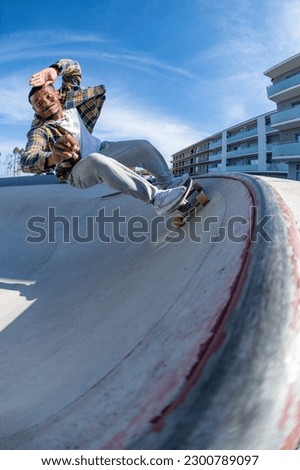 Surf skater performing a high speed turn on a skatepark during a sunny day. Royalty-Free Stock Photo #2300789097