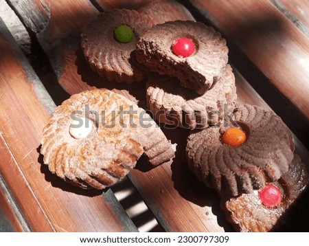 Pile of Jam Chocolate Biscuits with Colorful Toppings Under Bright Sun on Bamboo Background