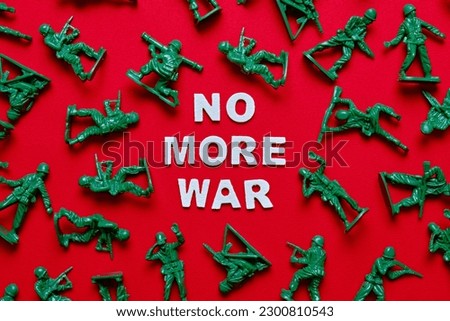 "NO MORE WAR" and toy soldiers on a red background. Royalty-Free Stock Photo #2300810543