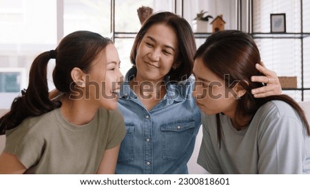 Middle aged mom smile look at two grown up kid child relax hug cuddle stroking with love care warm time. Asia people woman adult older mum parent sitting at home sofa sweet trust moment happy life. Royalty-Free Stock Photo #2300818601