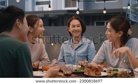 Middle aged mom smile joy look at young grown up kid child with love care good warm time. Asia people woman adult older mum parent sitting at home night dinner outdoor house party happy life moment. Royalty-Free Stock Photo #2300818697