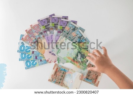 Selective focused , Full set of Kuwaiti Dinar bank paper notes. Kuwait dinar bank notes 0.25KWD, 0.5KWD, 1KWD, 5KWD, 10 KWD and 20 KWD. Kid trying to take the Kuwait dinar bank notes Royalty-Free Stock Photo #2300820407