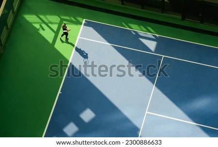 Aerial view of a woman playing tennis on a hard playground. Tennis sport concept photo.