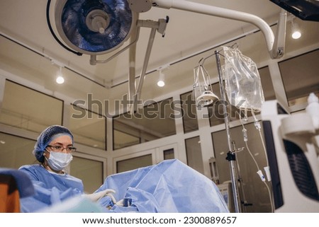 Professional female surgeon proctologist performing operation using special devices for colonoscopy in the operating room in hospital. Urgent surgical concept