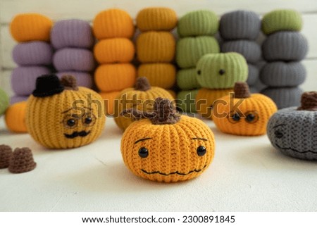 Knitted pumpkins of different colors, crocheted on a light background. Handmade for autumn decor. Halloween and Thanksgiving