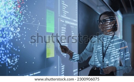 Young Female Teacher Giving a Data Science Presentation in a Dark Auditorium with Projecting Slideshow with Artificial Intelligence Neural Network Architecture. Business Startup and Education Concept Royalty-Free Stock Photo #2300906075