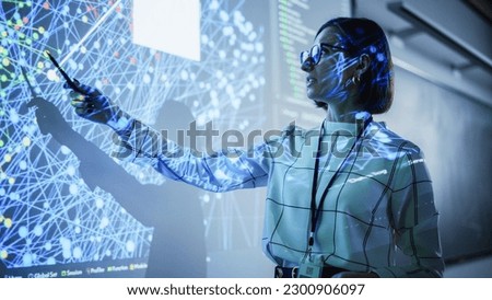 Young Female Teacher Giving a Data Science Presentation in a Dark Auditorium with Projecting Slideshow with Artificial Intelligence Neural Network Architecture. Business Startup and Education Concept Royalty-Free Stock Photo #2300906097