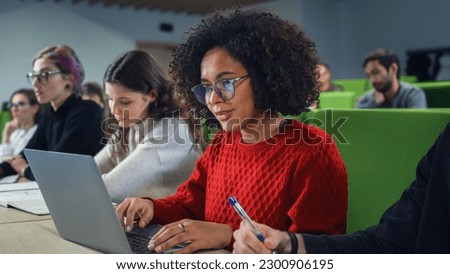 Beautiful Multiethnic African Female Student Studying in University with Diverse Classmates. Young Black Woman Using a Laptop Computer to Summarize the Lecture, Study at Home and Prepare for Exams Royalty-Free Stock Photo #2300906195