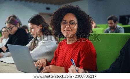 Portrait of an Empowered African Female Student Studying in University with Diverse Multiethnic Classmates. Young Happy Black Woman Looking at Camera and Smiling. Using Laptop Computer in Class