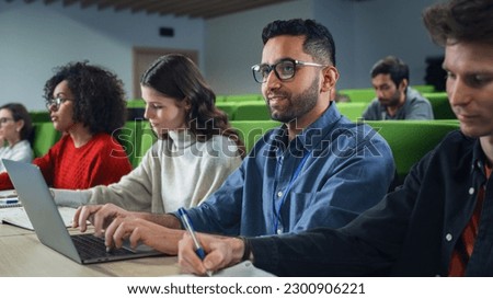 Smart Handsome Male Student Studying in University with Diverse Multiethnic Classmates. Young Man is Using a Laptop Computer to Summarize the Lecture, Study at Home and Pass the Exams Royalty-Free Stock Photo #2300906221