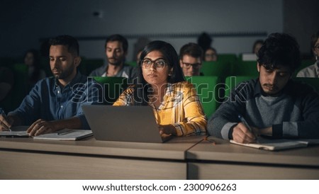 Portrait of a Smart Beautiful Indian Female Student Studying in University with Diverse Multiethnic Classmates. Young Woman Using Laptop Computer and Taking Notes During the Lecture Royalty-Free Stock Photo #2300906263
