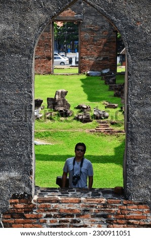 Thai men photographer travelers people travel visit and use digital camera shooting ancient ruins buildings antique architecture of Wat Phra Sri Rattana Mahathat at Lopburi city in Lop Buri, Thailand
