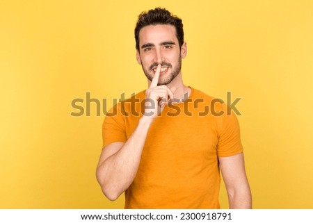 Young man with happy expression gesturing for silence in a professional studio setting Royalty-Free Stock Photo #2300918791