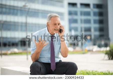 Angry senior business man yelling at the phone outdoor Royalty-Free Stock Photo #2300924433