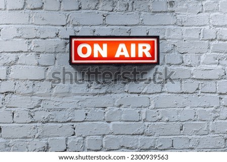 a red on air sign against a white brick wall Royalty-Free Stock Photo #2300939563