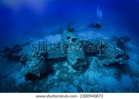 A scuba diver explores a sunken world war two fighter propeller airplane at the seabed of the Aegean Sea, Naxos island, Greece Royalty-Free Stock Photo #2300940873