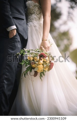 A newly married couple in embrace with the bridge holding a pretty bouquet in a vertical shot Royalty-Free Stock Photo #2300941109