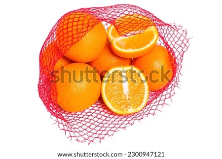 Fresh and juicy oranges in a red retail mesh bag isolated on white background. One orange is sliced in half.