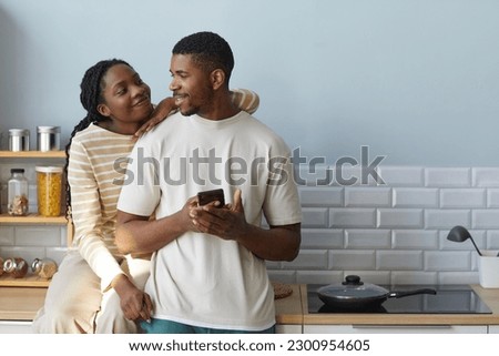 African American couple smiling and talking to each other while using smartphone, they spending time together at home Royalty-Free Stock Photo #2300954605