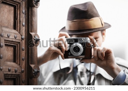 Detective, camera and spy with man in studio for surveillance, reporter and investigation. Photography, press and secret with male agent on white background for vintage, paparazzi and journalist
