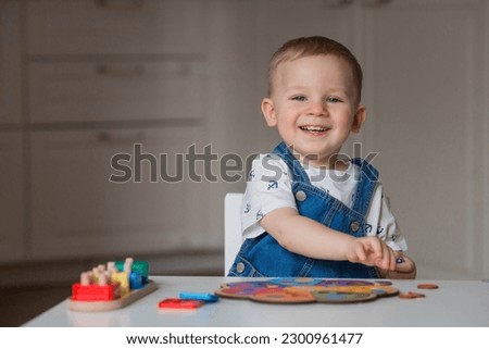 A little boy is playing educational logic games. Children's wooden toys. Sorter. Montessori for child development. Royalty-Free Stock Photo #2300961477