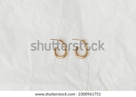 Gold women's earrings on a background of white crumpled paper close-up. Images for your design