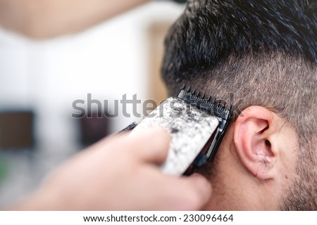 men's hairstyling and haircutting with hair clipper in a barber shop or hair salon Royalty-Free Stock Photo #230096464