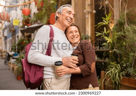 Happy Vacation Travel. Cheerful Mature Spouses Enjoying Their Lisbon Getaway, Hugging Posing With Backpack And Paper Coffee Cups Outside. Tour Offer For Retired People Concept Royalty-Free Stock Photo #2300969227