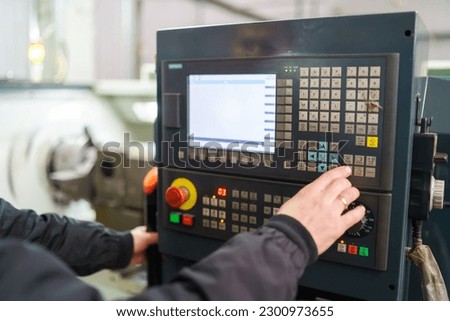 Cropped shot of machine operator hand turns on control panel of industrial machine. Close up of technician in push button on control pannel Royalty-Free Stock Photo #2300973655