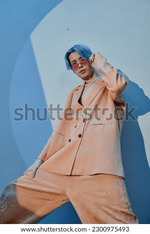 Vertical image of Asian man in stylish suit looking at camera against blue background Royalty-Free Stock Photo #2300975493