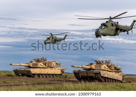 The photo depicts a powerful combination of American M1 Abrams tanks Mi-24 helicopters, which have been deployed to support the Ukrainian military in their ongoing conflict, providing advanced fir Royalty-Free Stock Photo #2300979163