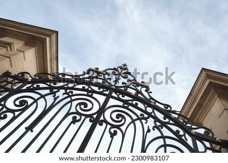 Stylish wrought iron gate and stone pillars Royalty-Free Stock Photo #2300983107