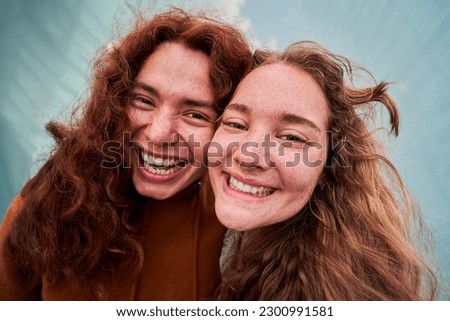 Cheerful close up portrait of two people putting the heads together looking at camera with big smile. Blonde girl and ginger boy taking a selfie. Royalty-Free Stock Photo #2300991581