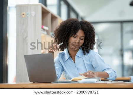 Young American businesswoman working on the laptop with documents and stressing at work from working on financial documents in office Overworked woman concept.