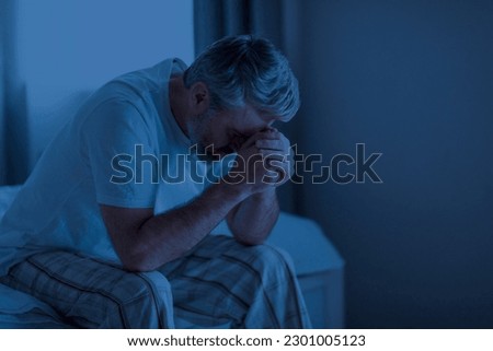 Insomnia, sleeping disorder concept. Sleepless depressed middle aged man wearing pajamas sitting on bed at home, touching his head, cant sleep, awake late at night, copy space Royalty-Free Stock Photo #2301005123