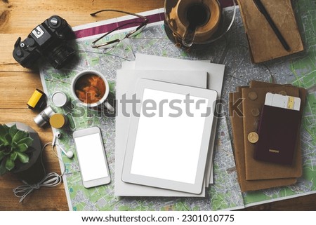 Travel concept flat lay table top shot on wooden background with magazine stack and white blank screen digital tablet, phone.