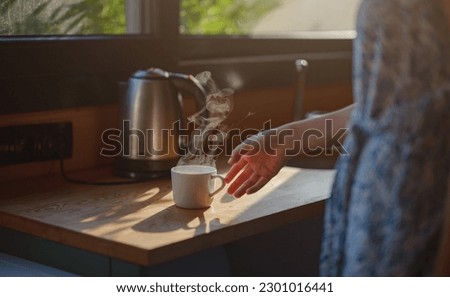 Woman is drinking coffee , morning routine. Tiny house. First property. Small apartment interior design. Minimalism. Moving in. Living alone. Charming trailer house with the morning sun Royalty-Free Stock Photo #2301016441