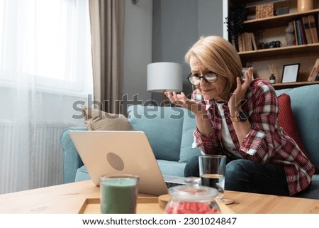 Worried middle-aged 70s lady sit on sofa in living room read negative unexpected news on laptop, anxious mature woman rest on couch feel distressed with unpleasant bad message on computer Royalty-Free Stock Photo #2301024847