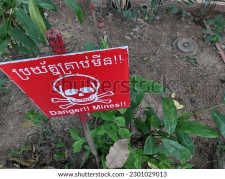 caution land mine sign and a mine on the ground in Cambodia 