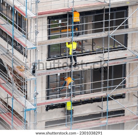 Glazier installing windows on a commercial building. Royalty-Free Stock Photo #2301038291