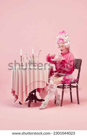Sweet cotton breakfast. Portrait of elegant princess, queen wearing elegant clothes and wig eating over pink background. Concept of comparison of eras, modernity and renaissance, beauty, history Royalty-Free Stock Photo #2301044023