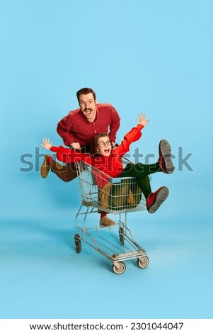 Adventure time. Portrait with couple, man and pretty woman having a shopping cart race over blue color studio background. concept of fun, emotions, crazy concessions, love, relationship, family, ad Royalty-Free Stock Photo #2301044047