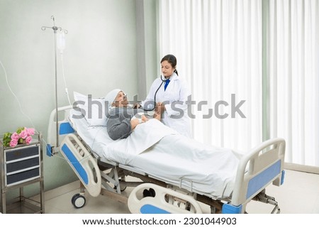 Indian doctor check heat beat of senior cancer patient undergoing course of chemotherapy in hospital. health care concept. Royalty-Free Stock Photo #2301044903